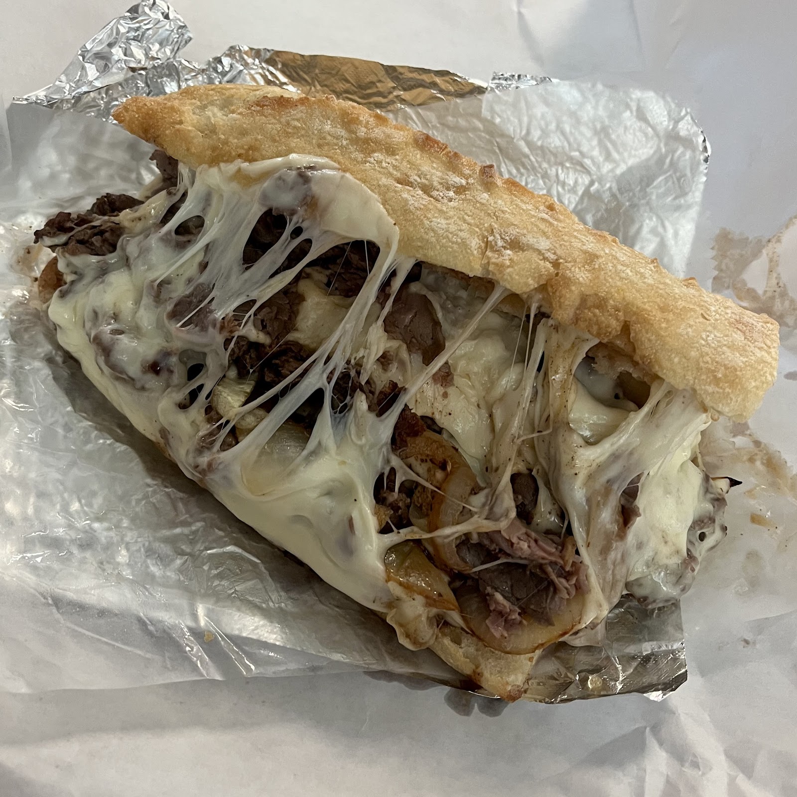 Philly cheesesteak with a melted cheese pull on New York bread