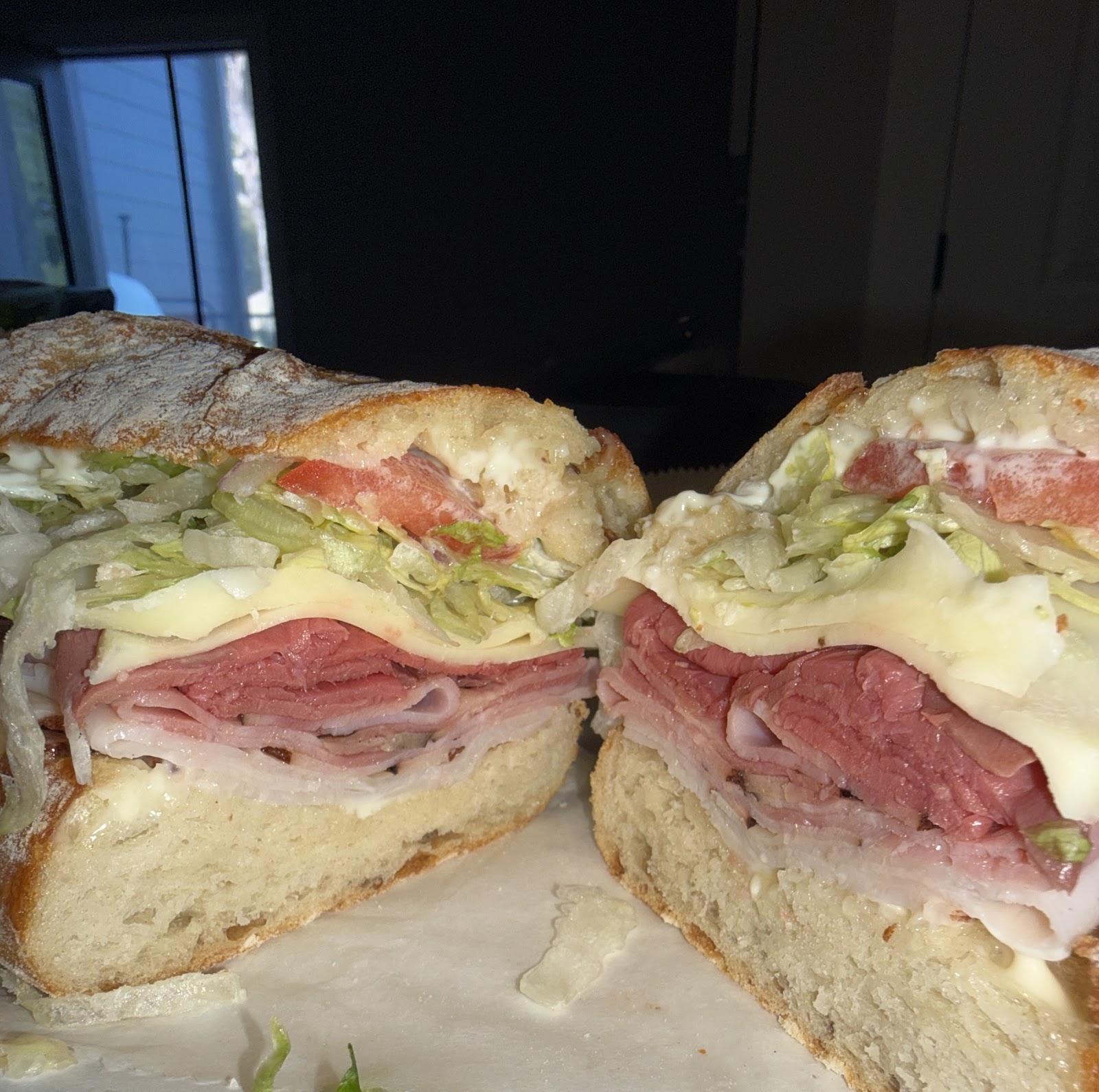 An overstuffed Italian sandwich cut in half, showing the stacked meats and cheese